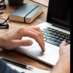 Anonymous person typing on laptop, ostensibly searching for journals